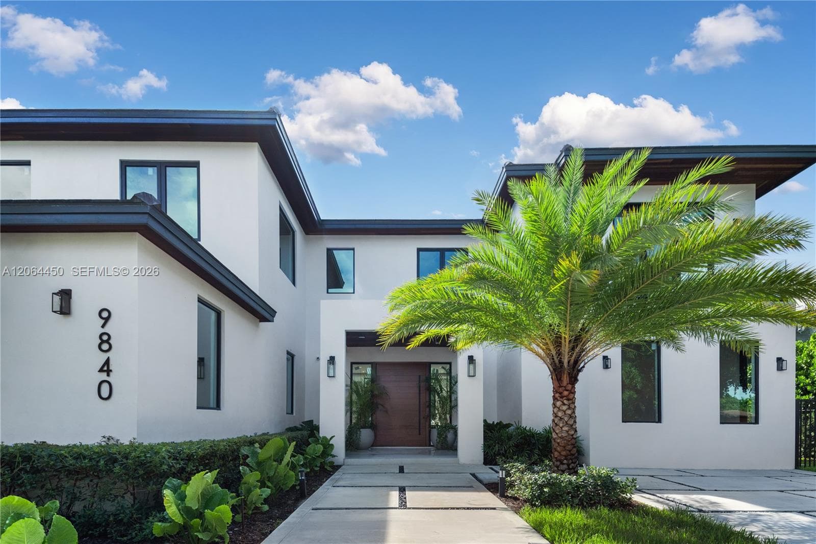 Modern two story residence framed by mature royal palms and manicured landscaping