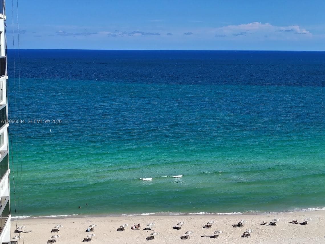 High-rise exterior featuring a direct oceanfront position, expansive windows, and a private balcony overlooking the shoreline