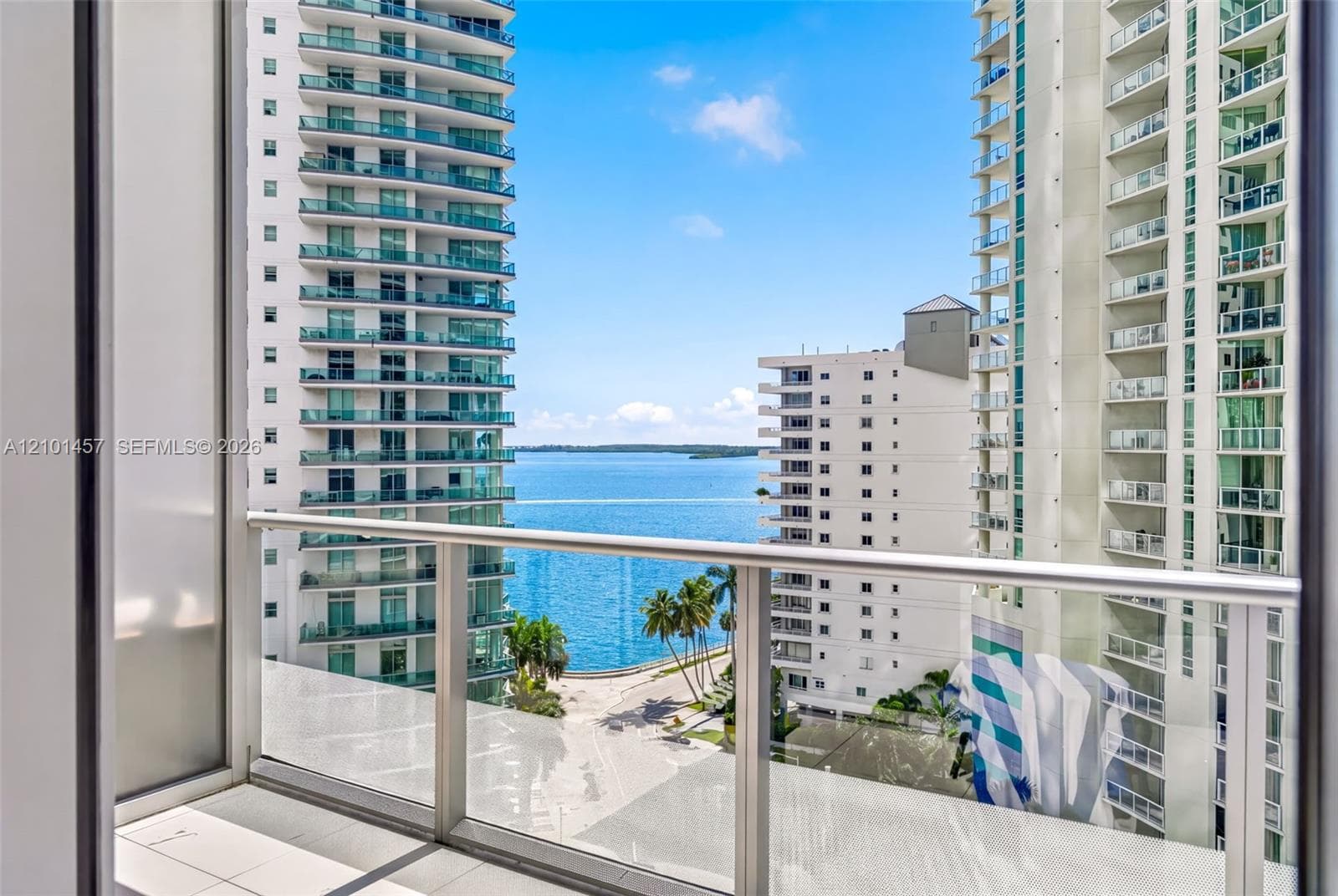 Private balcony featuring glass panel railings and tile flooring with exposure to water and urban surroundings