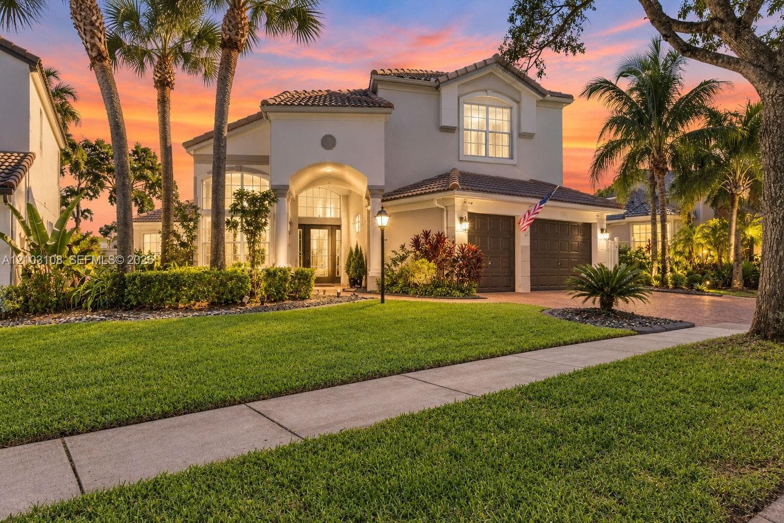 Two-story exterior featuring an arched entryway with columns, a tiled roof, and a paved driveway