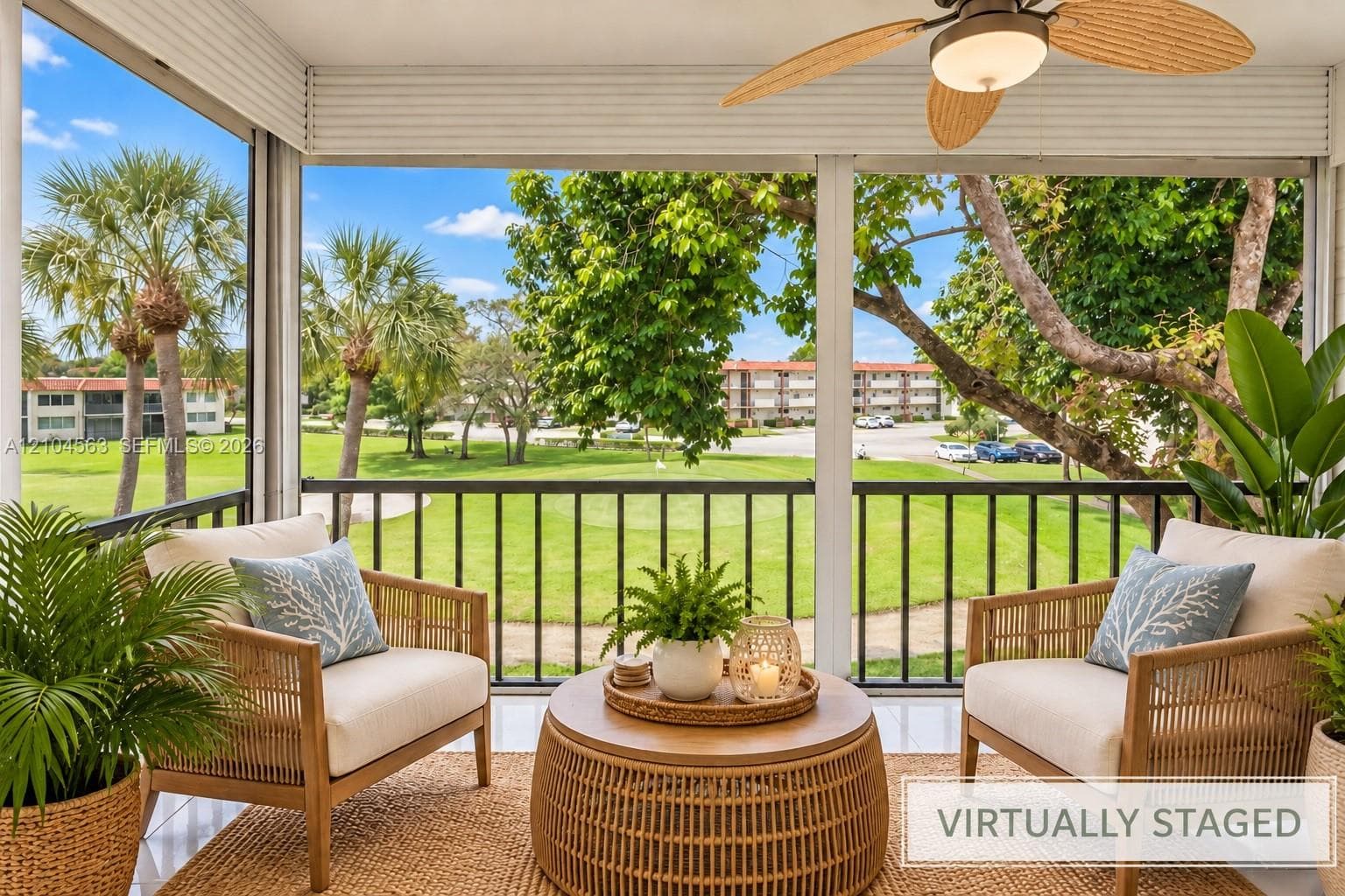 Screened porch featuring a ceiling fan, black railings, and a green landscape backdrop