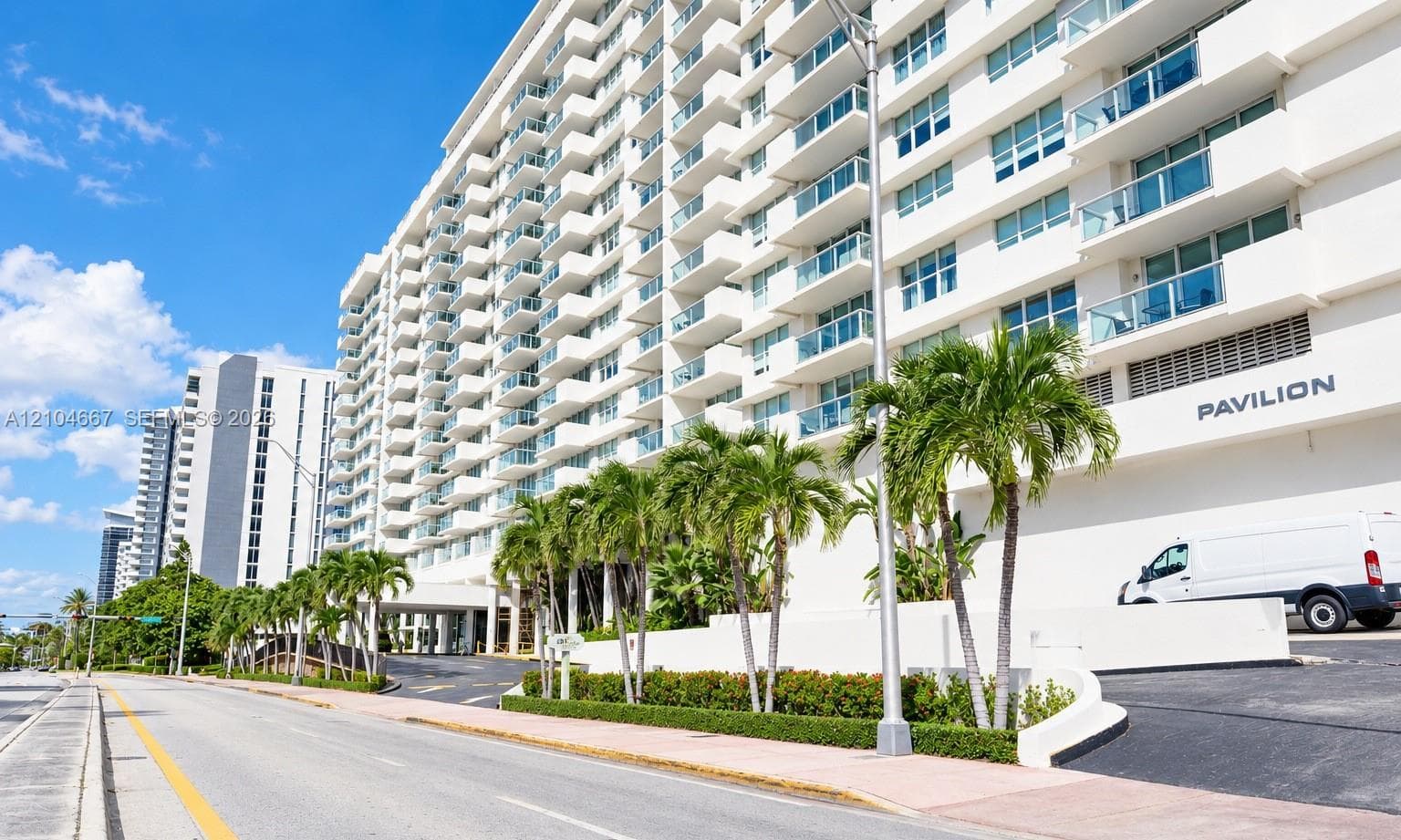 High-rise exterior featuring private balconies, floor-to-ceiling glass panels, manicured landscaping, and a multi-level concrete facade