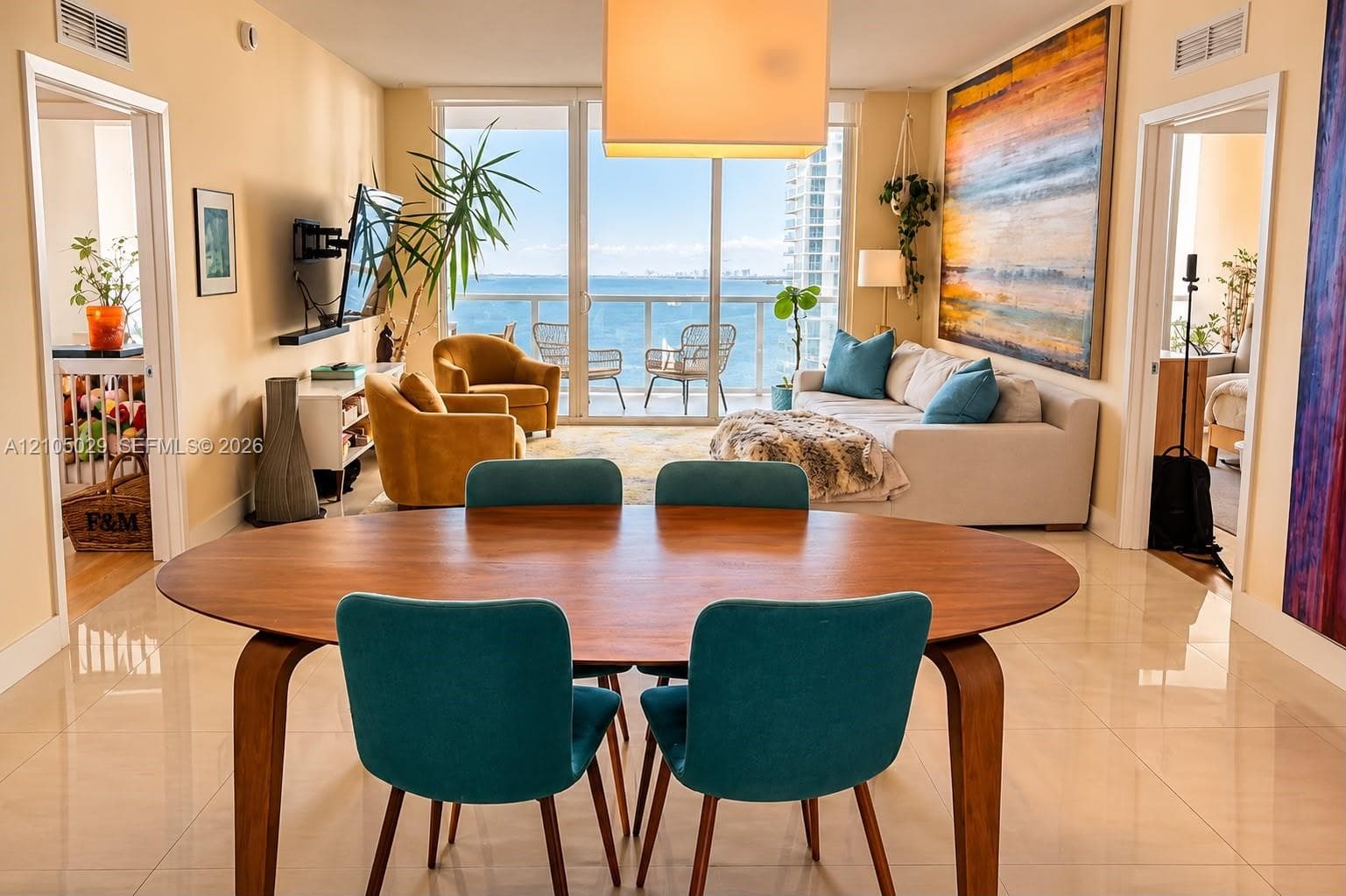 Open-concept living area featuring large-format tile flooring, floor-to-ceiling glass sliding doors, and a private balcony