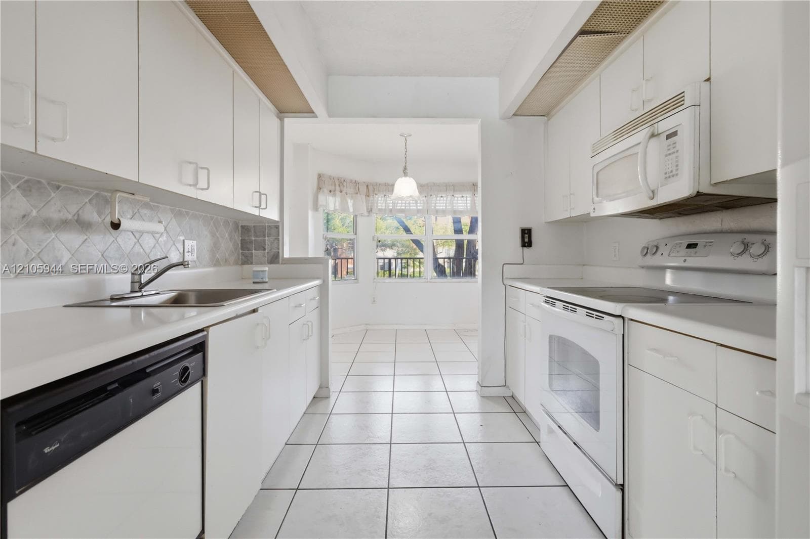 Kitchen featuring white cabinetry, solid-surface countertops, tile backsplash, built-in appliances, and ceramic tile flooring