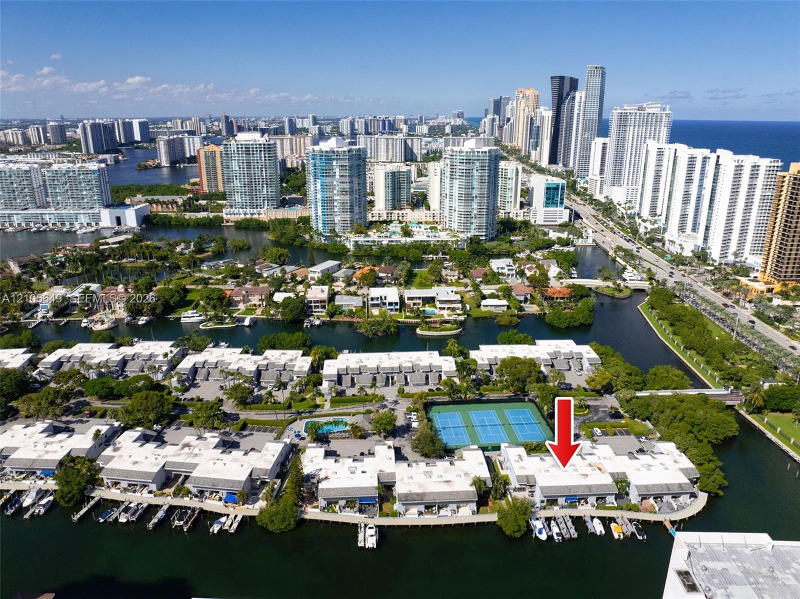 Aerial perspective featuring waterfront residential property with private boat slips, direct canal access, and communal tennis courts