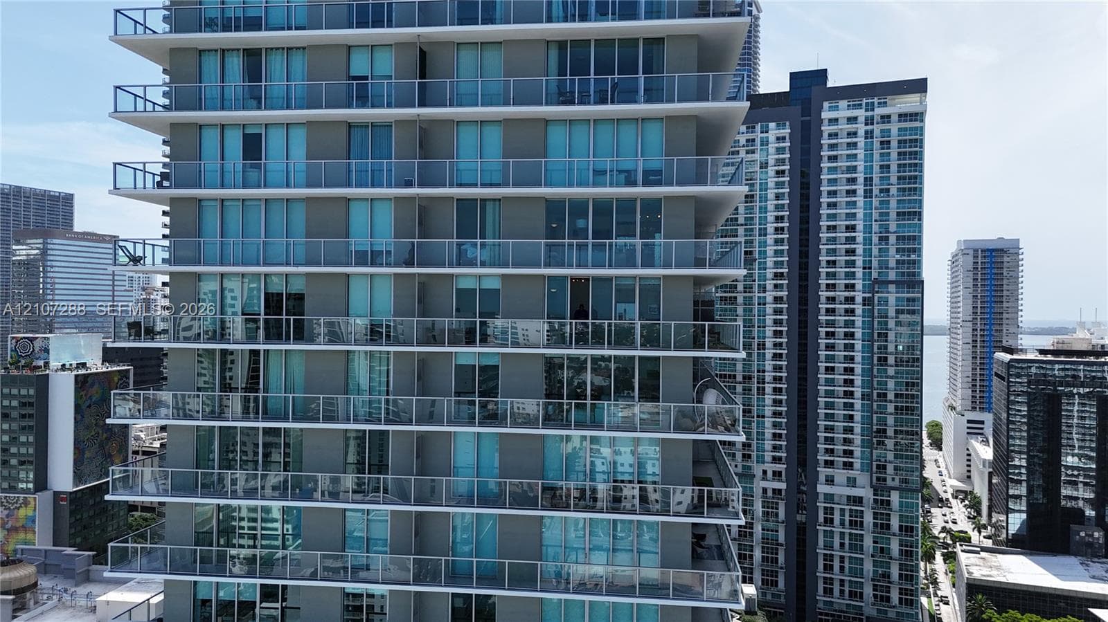 High-rise building exterior featuring floor-to-ceiling glass windows and multiple private balconies with glass railings
