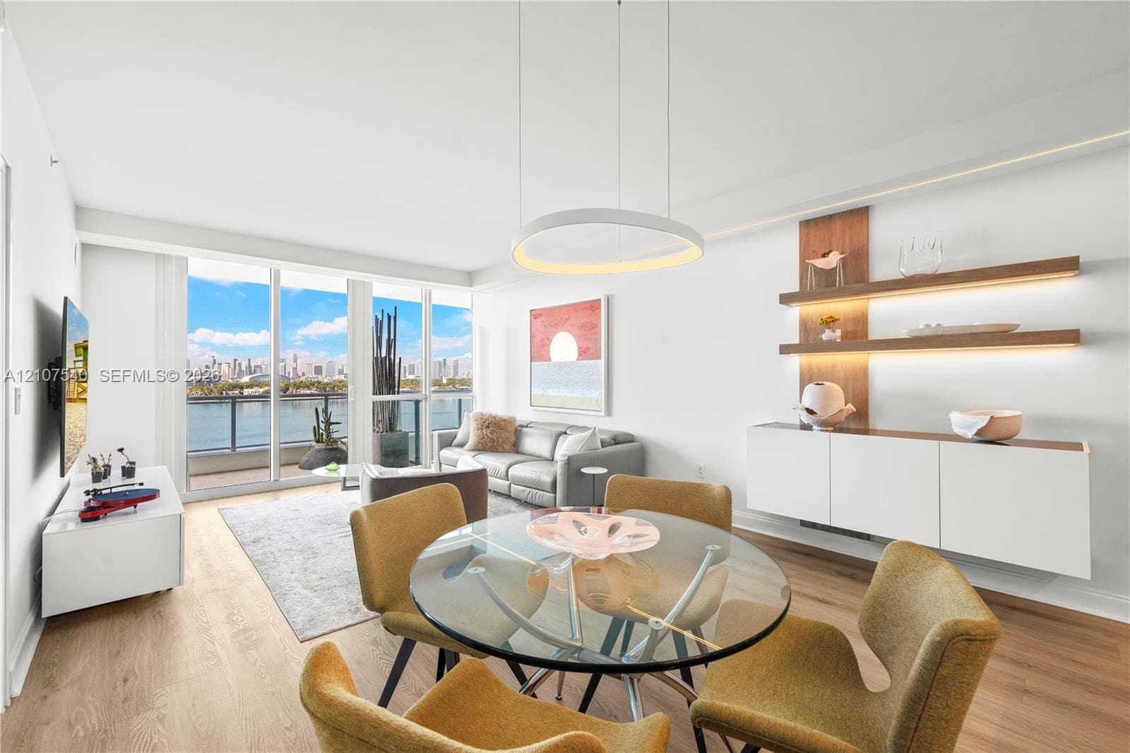 Open-concept living space featuring floor-to-ceiling windows, wood-finish flooring, modern circular LED integrated lighting built into custom soffits, and built-in floating wall shelving with integrated LED lighting