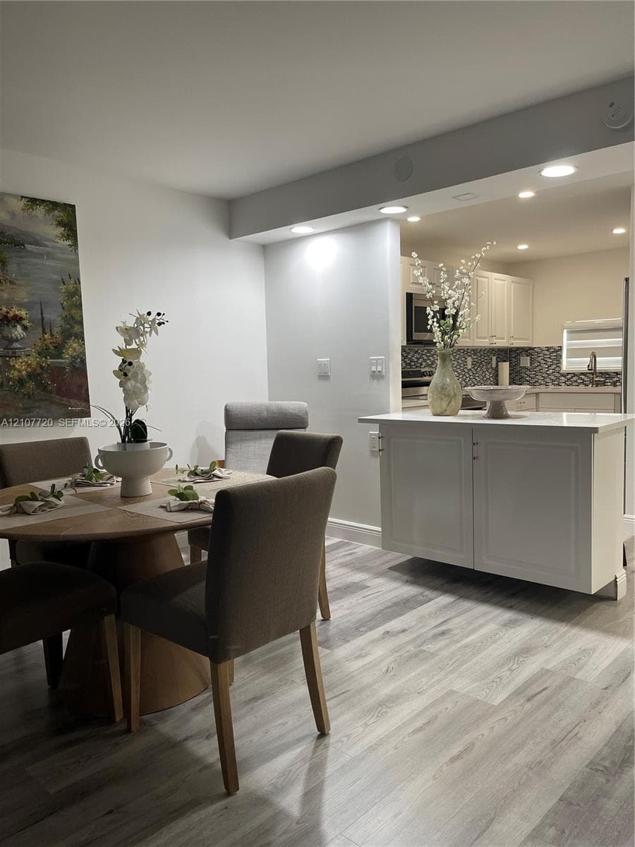 Wood-finish flooring, white cabinetry, quartz-style countertop, and recessed ceiling lighting