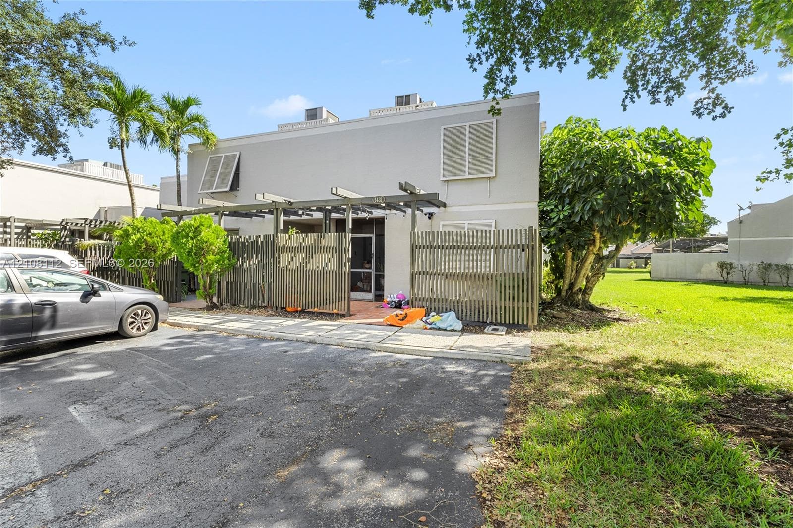 Two-story exterior featuring a pergola, fenced patio, paved walkway, and white louvered shutters