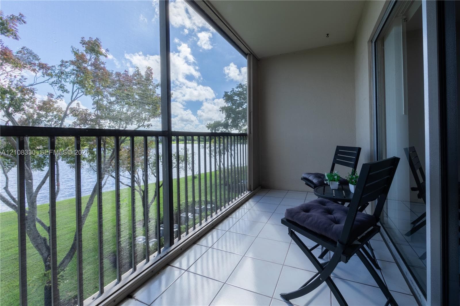 Screened-in balcony featuring tile flooring, metal railings, and direct water frontage