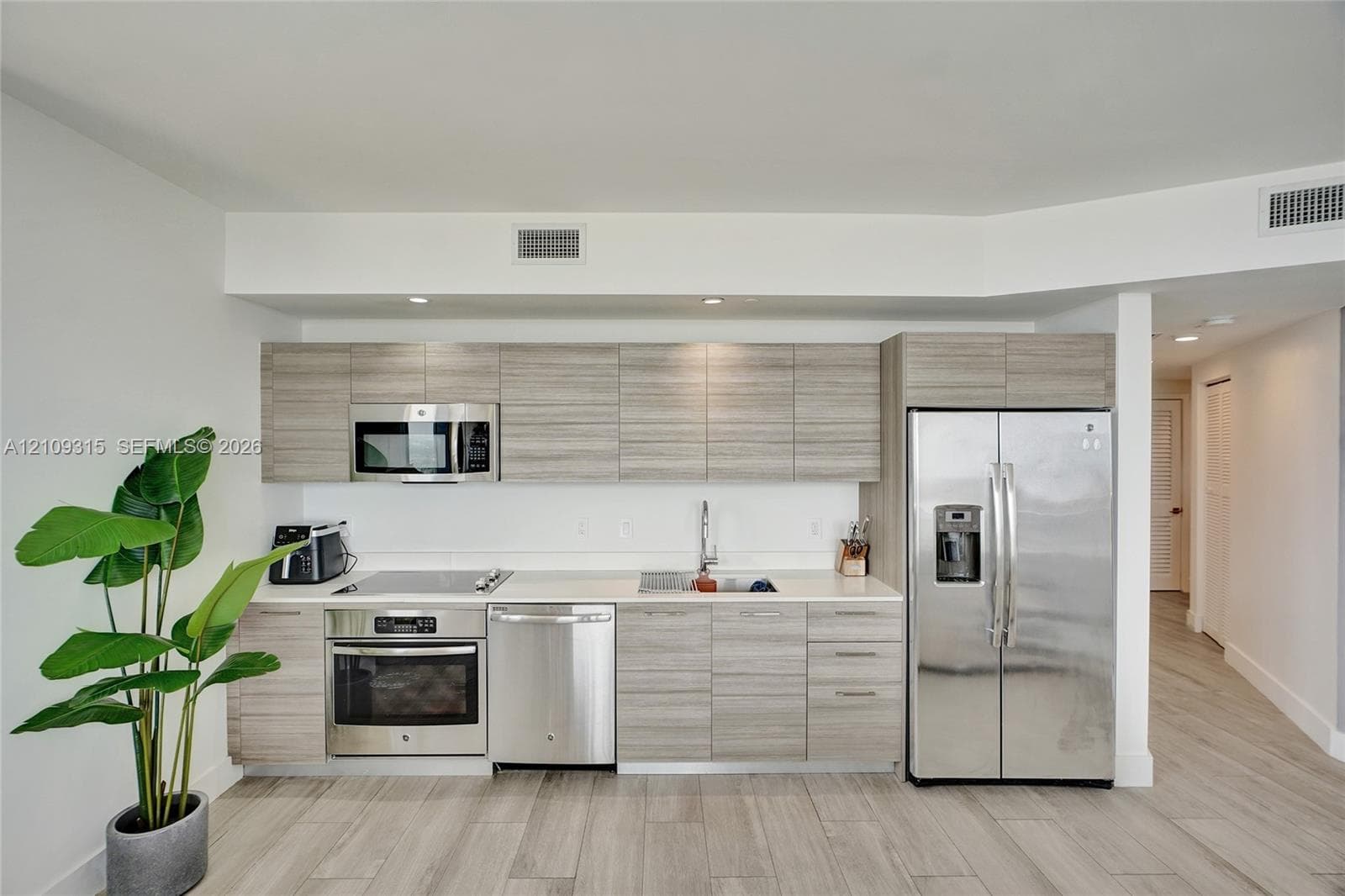 Kitchen featuring wood-finish cabinetry, stainless steel appliances, solid-surface countertops, and wood-finish flooring
