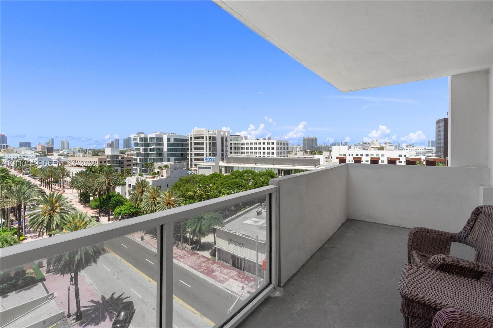 Private covered balcony featuring concrete flooring and a glass-paneled railing