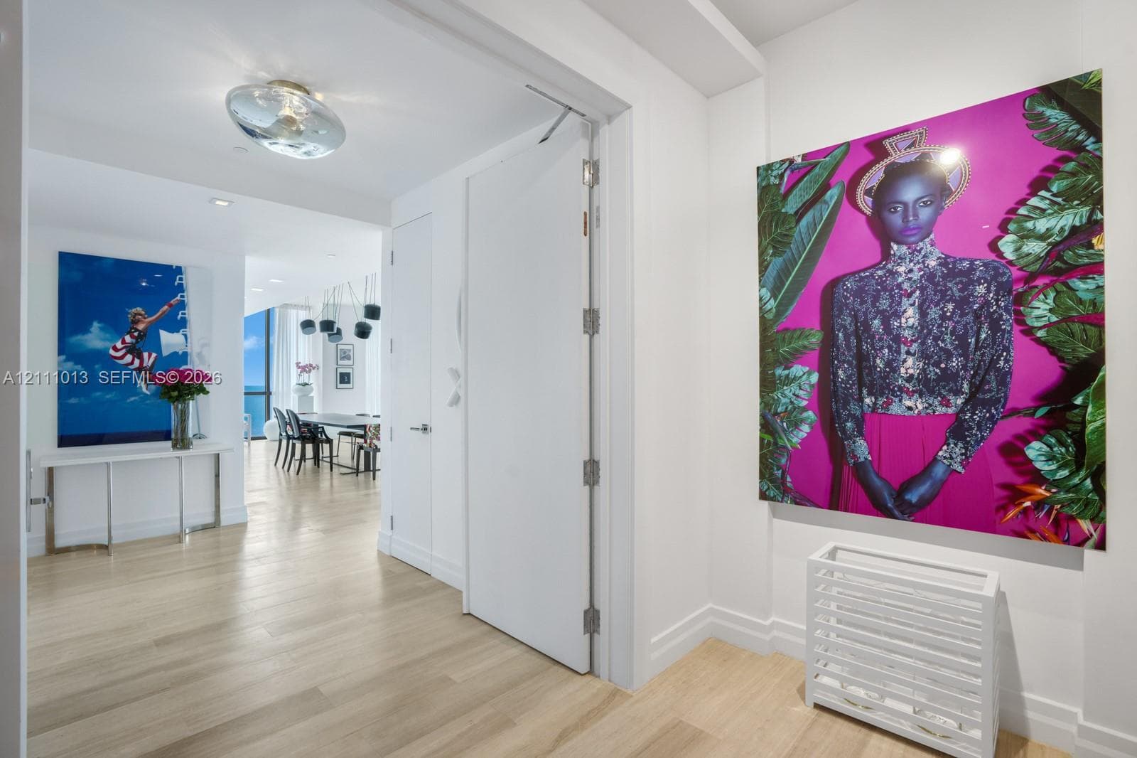 Interior hallway featuring wood-finish flooring, smooth-finish walls, ceiling-mounted circular lighting, and a full-height interior door with metal hinges